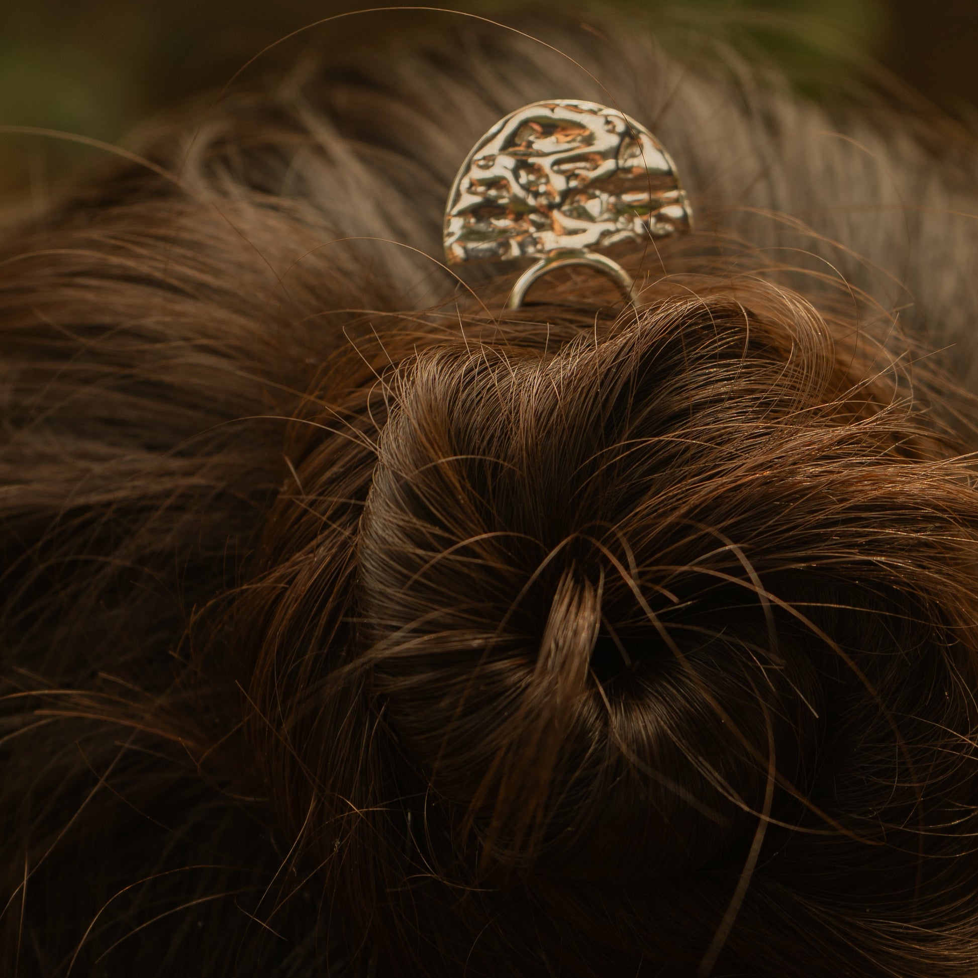 Close-up of a hair bun with a decorative hair clip against a blurred background
