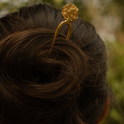 Gold hairpin in a bun with a blurred natural background