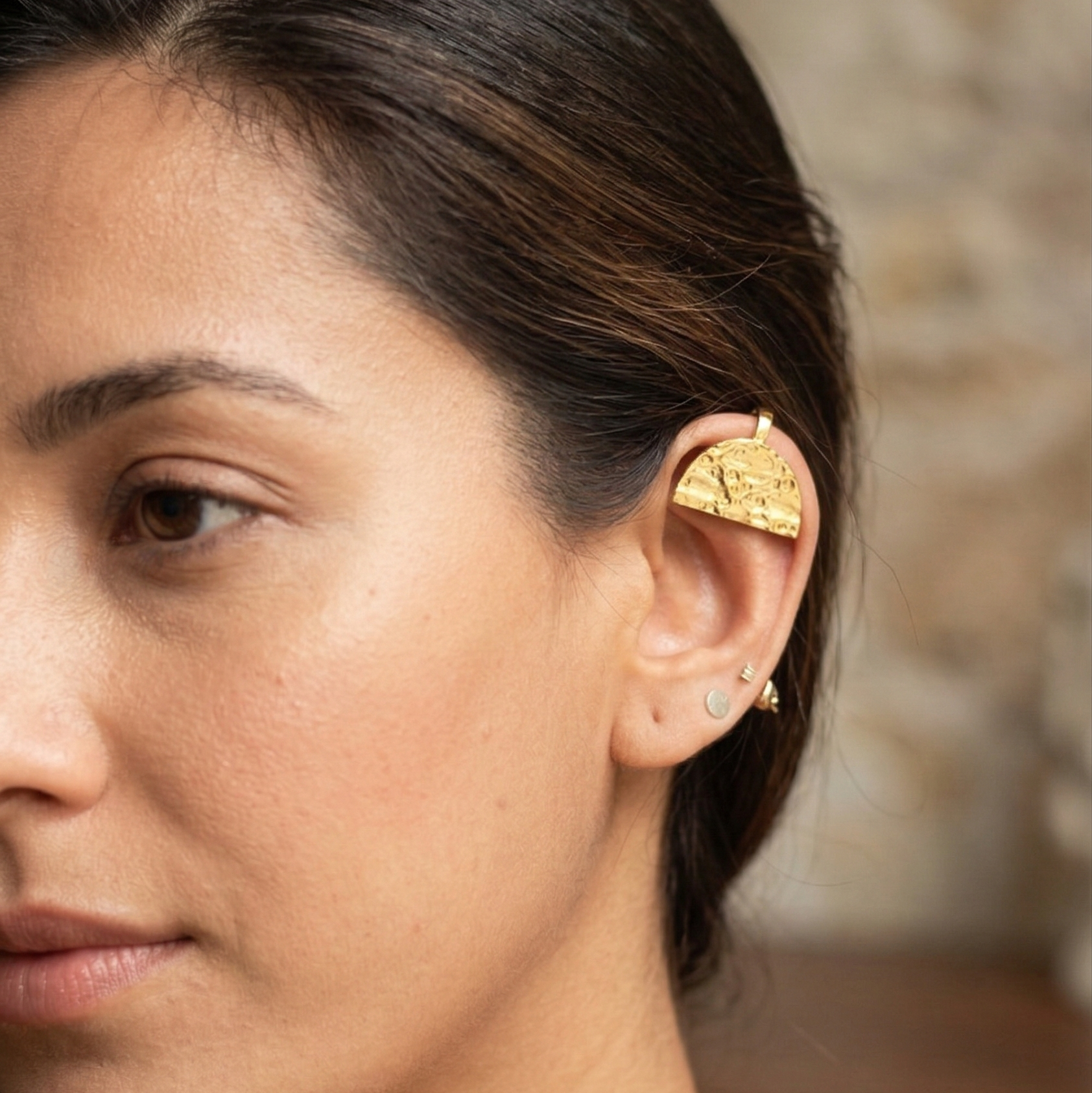 Close-up of a woman wearing a gold earring with a blurred background