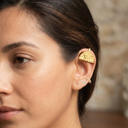Close-up of a woman wearing a gold earring with a blurred background