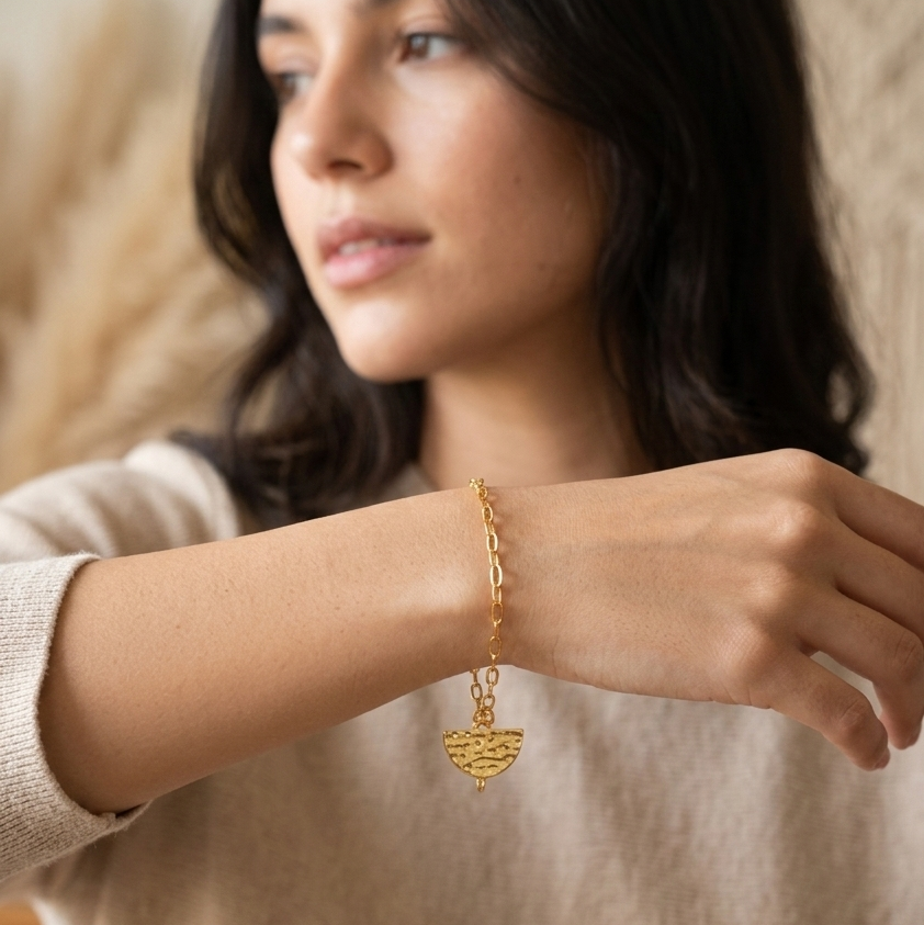 Woman wearing a gold bracelet with a neutral background