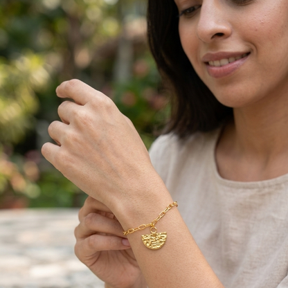 Woman wearing a gold bracelet with a heart design outdoors