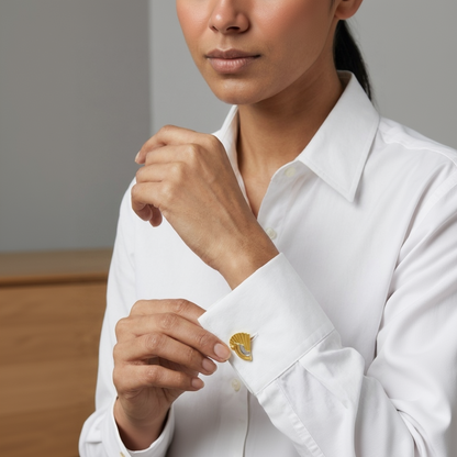 A close-up of a woman wearing a white long-sleeve dress shirt and adjusting a gold cufflink on her left sleeve.