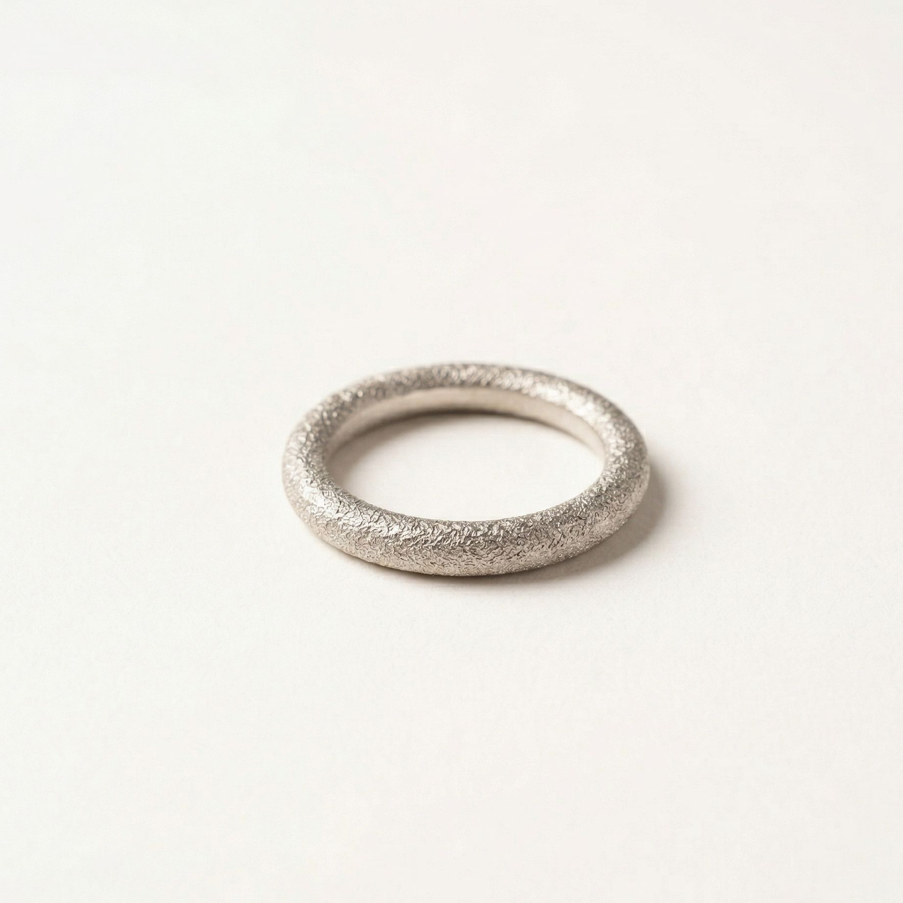 Silver ring with textured surface on a white background