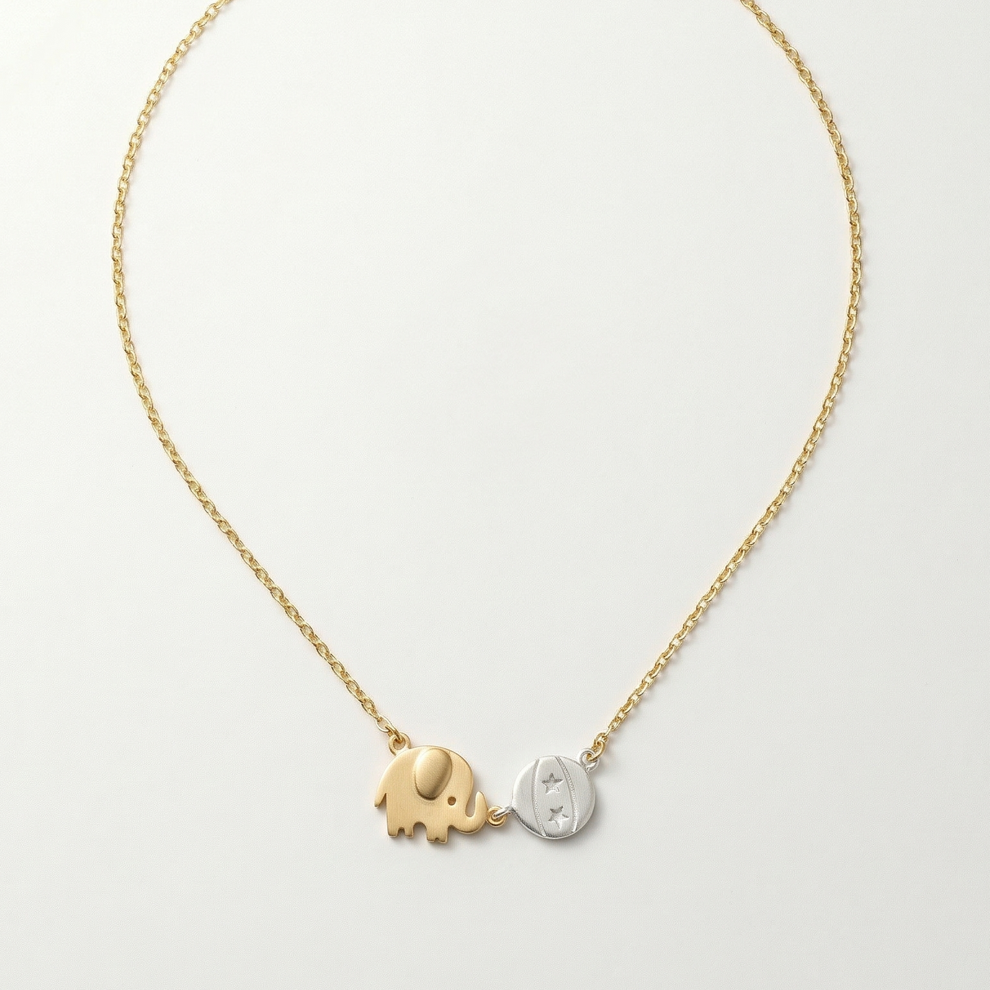 Gold and silver elephant pendant necklace on a light gray background
