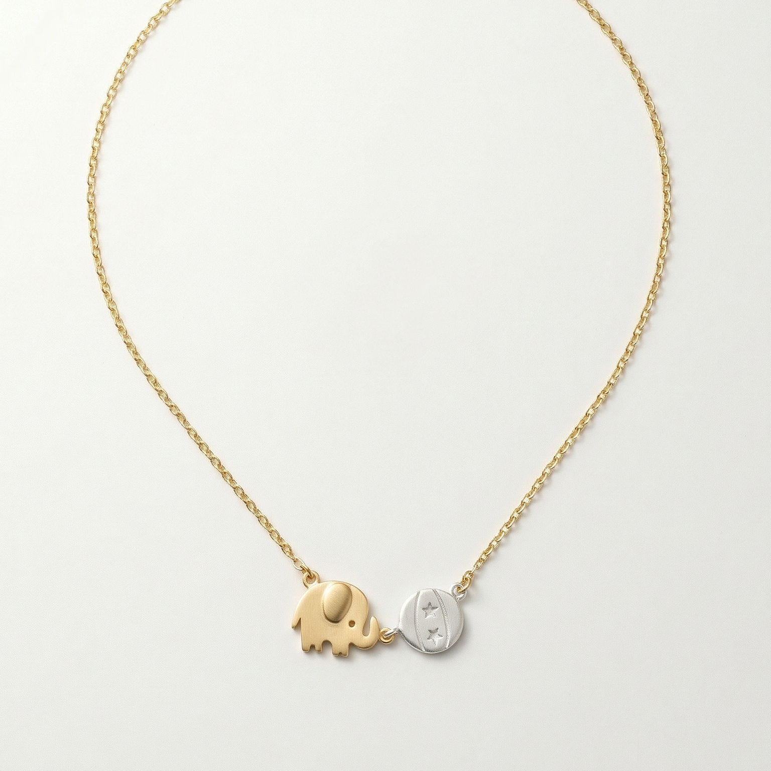Gold and silver elephant pendant necklace on a light gray background