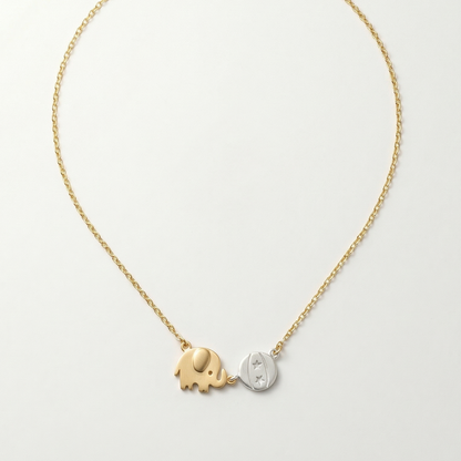 Gold and silver elephant pendant necklace on a light gray background