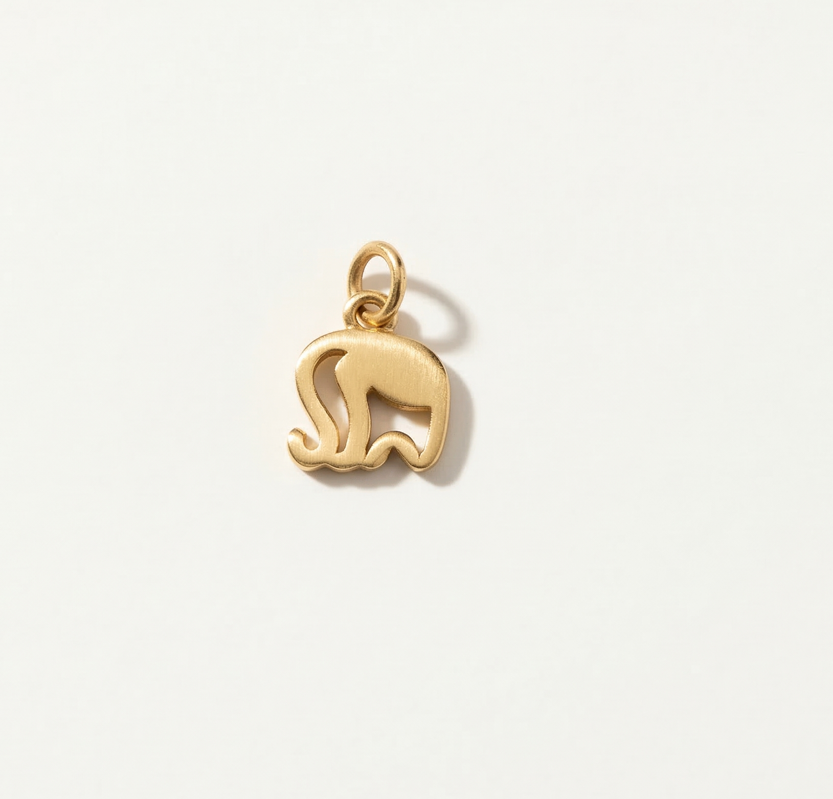 Gold elephant pendant on a light beige background