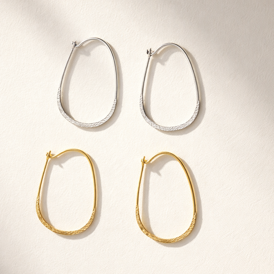 Two pairs of hoop earrings, one gold and one silver, on a light background.