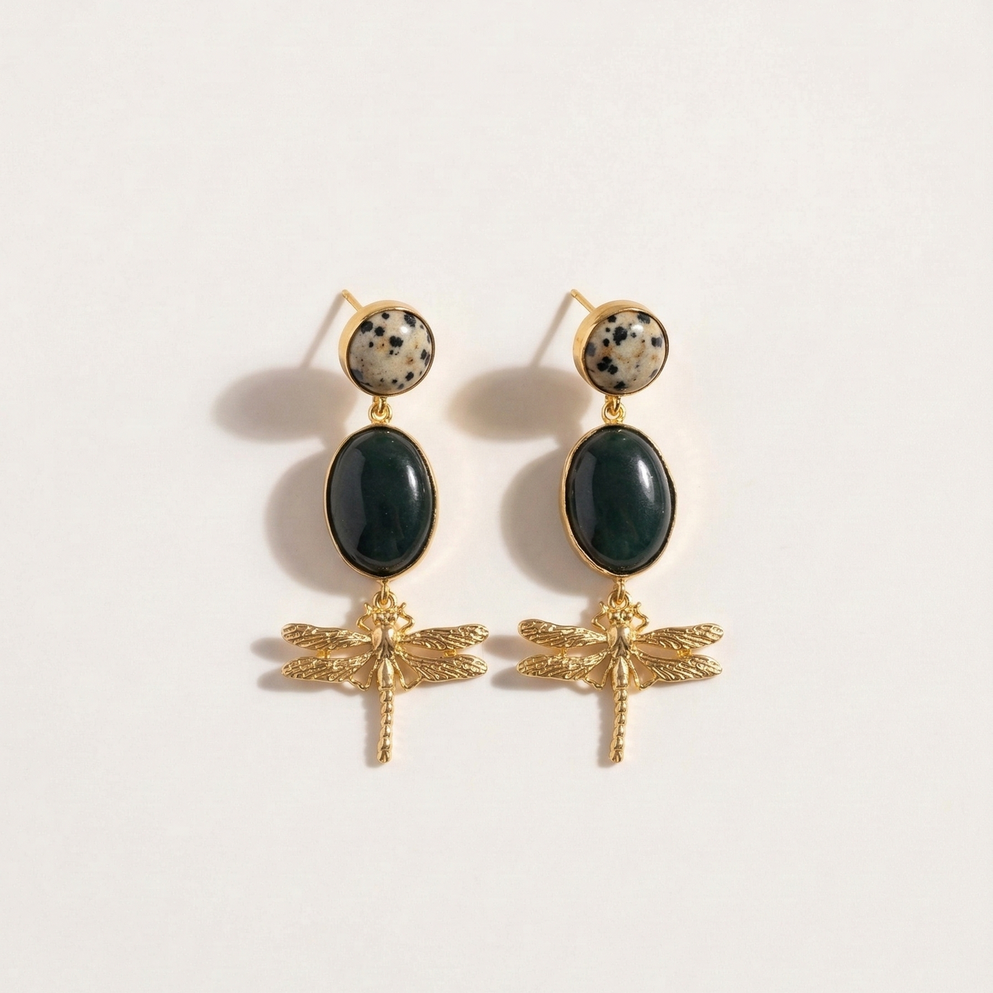 Pair of earrings with gold dragonfly designs and dark green stones on a white background