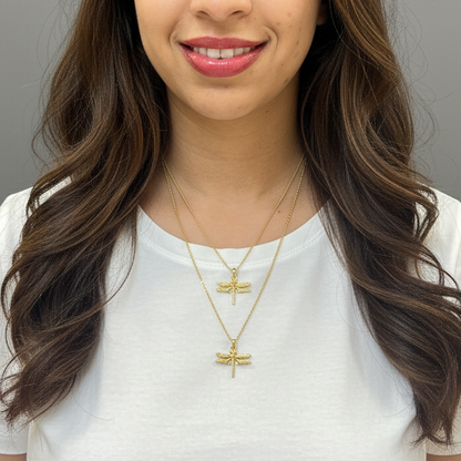 Woman wearing a white shirt and gold necklaces with dragonfly pendants against a gray background