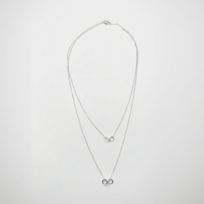 Silver necklace with two small pendants on a white background