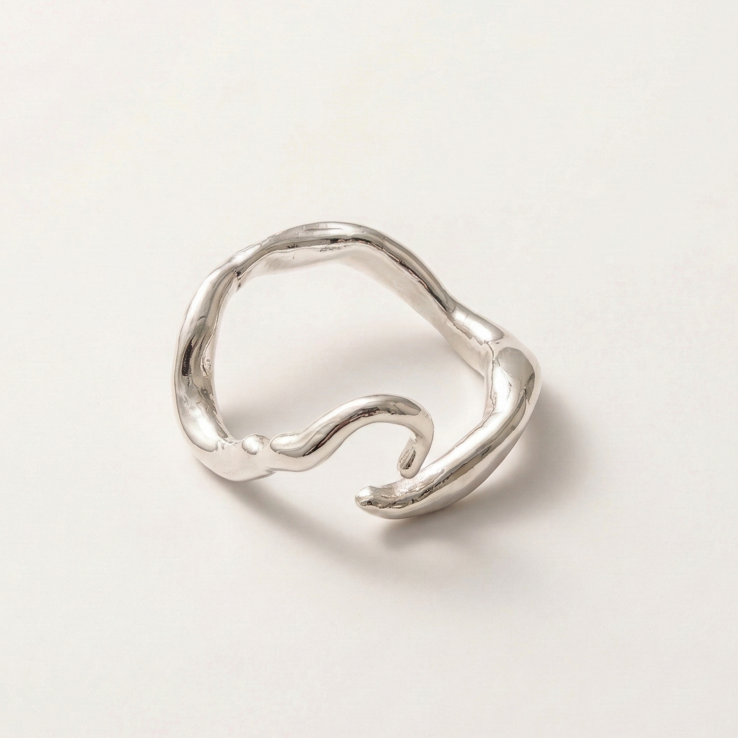 Silver ring with a wavy design on a light gray background