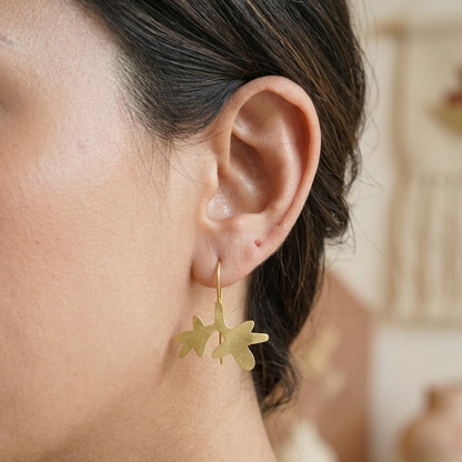 Close-up of a person wearing gold earrings with a blurred background