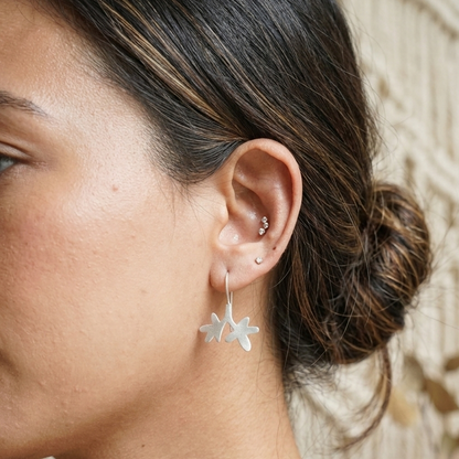 Close-up of a woman wearing star-shaped earrings with a neutral background