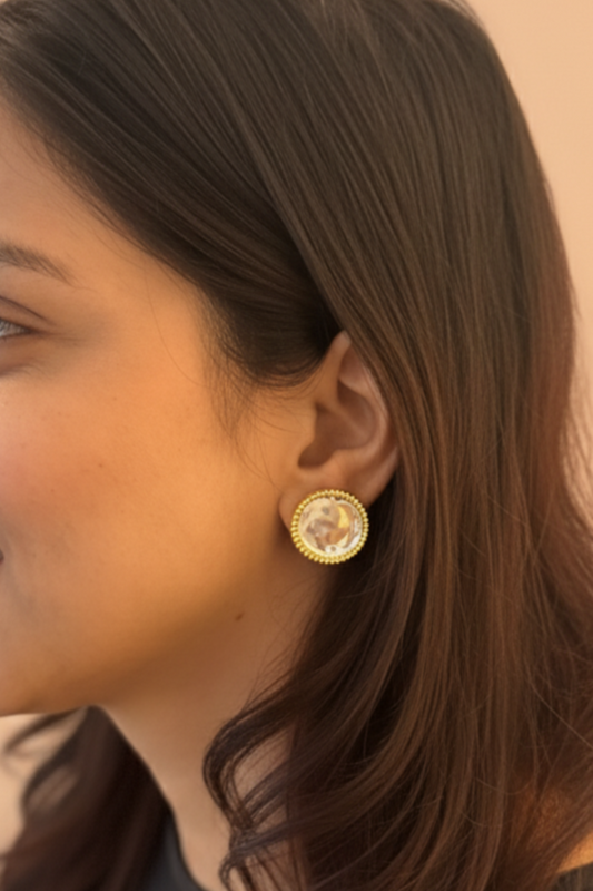 Woman wearing gold earrings with a neutral background