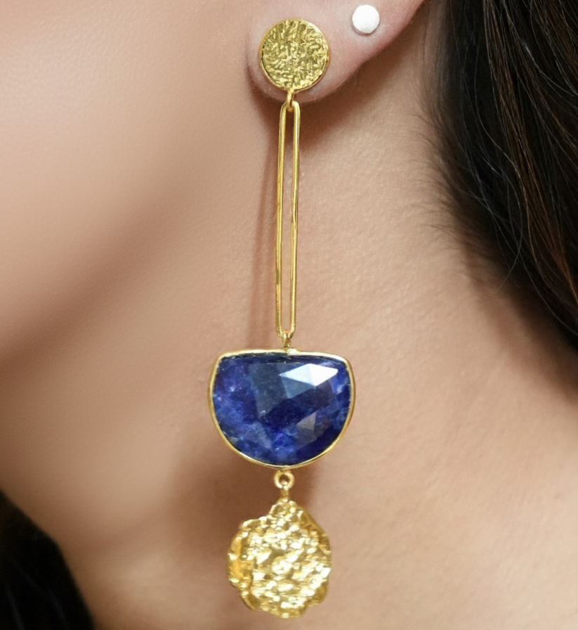 Gold and blue earring worn by a person