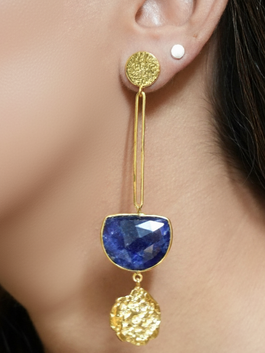 Gold and blue earring worn by a person