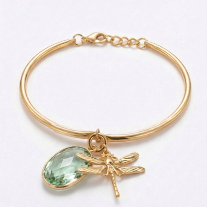 Gold bracelet with green teardrop charm and dragonfly detail on a white background