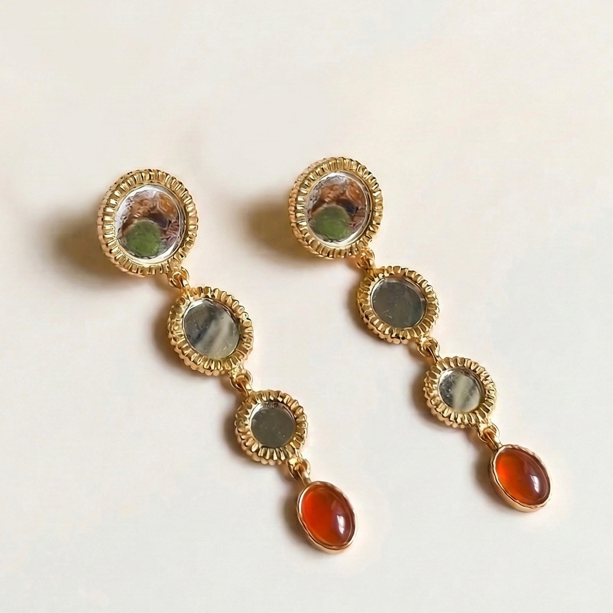 Gold earrings with multicolored gemstones on a light background