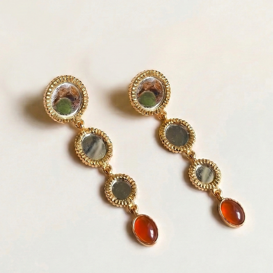 Gold earrings with multicolored gemstones on a light background