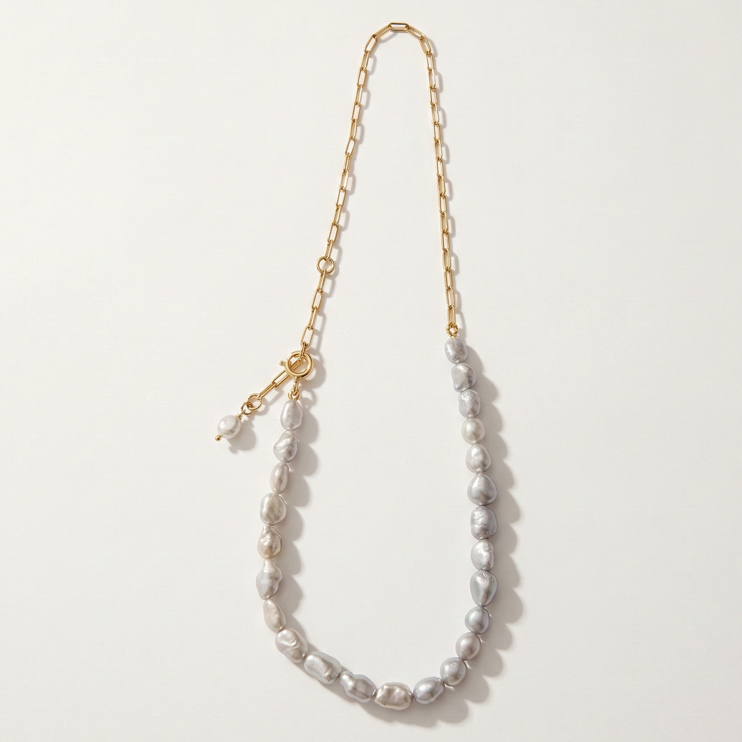 Pearl necklace with gold chain on a light gray background
