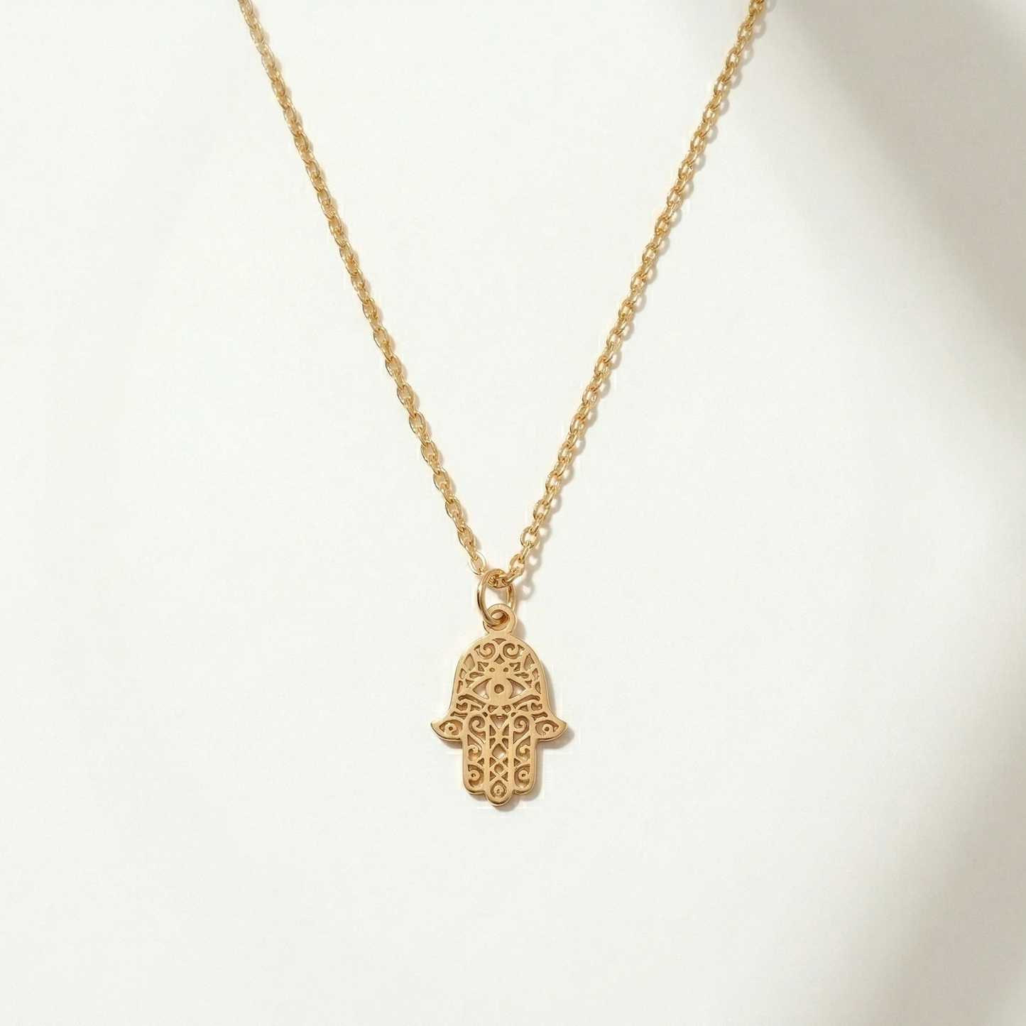 Gold necklace with a hamsa hand pendant on a white background