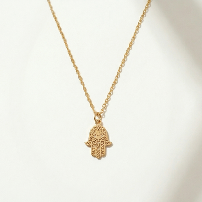 Gold necklace with a hamsa hand pendant on a white background