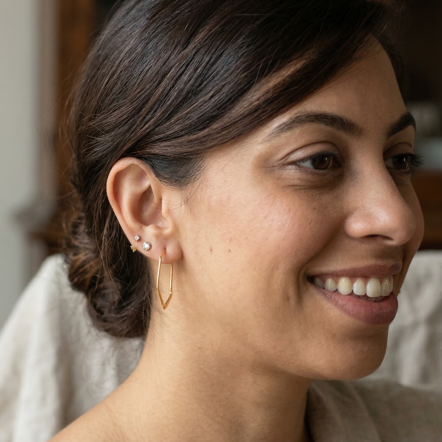 Woman wearing hexagon hoop earrings with a blurred background