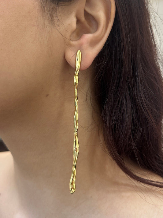 Close-up of a person wearing a gold earring with a neutral background