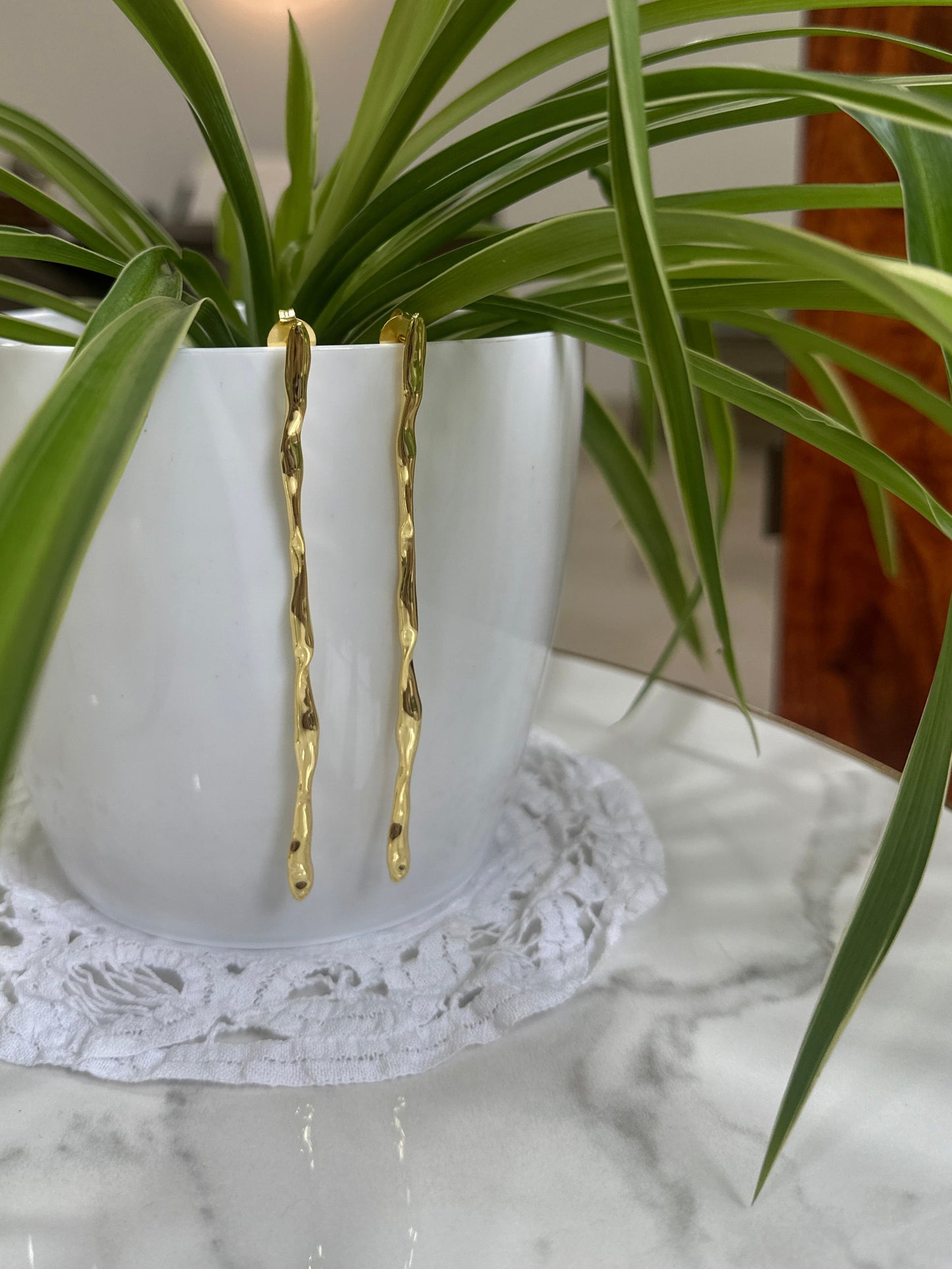 Gold hairpin on a white vase with green plant leaves
