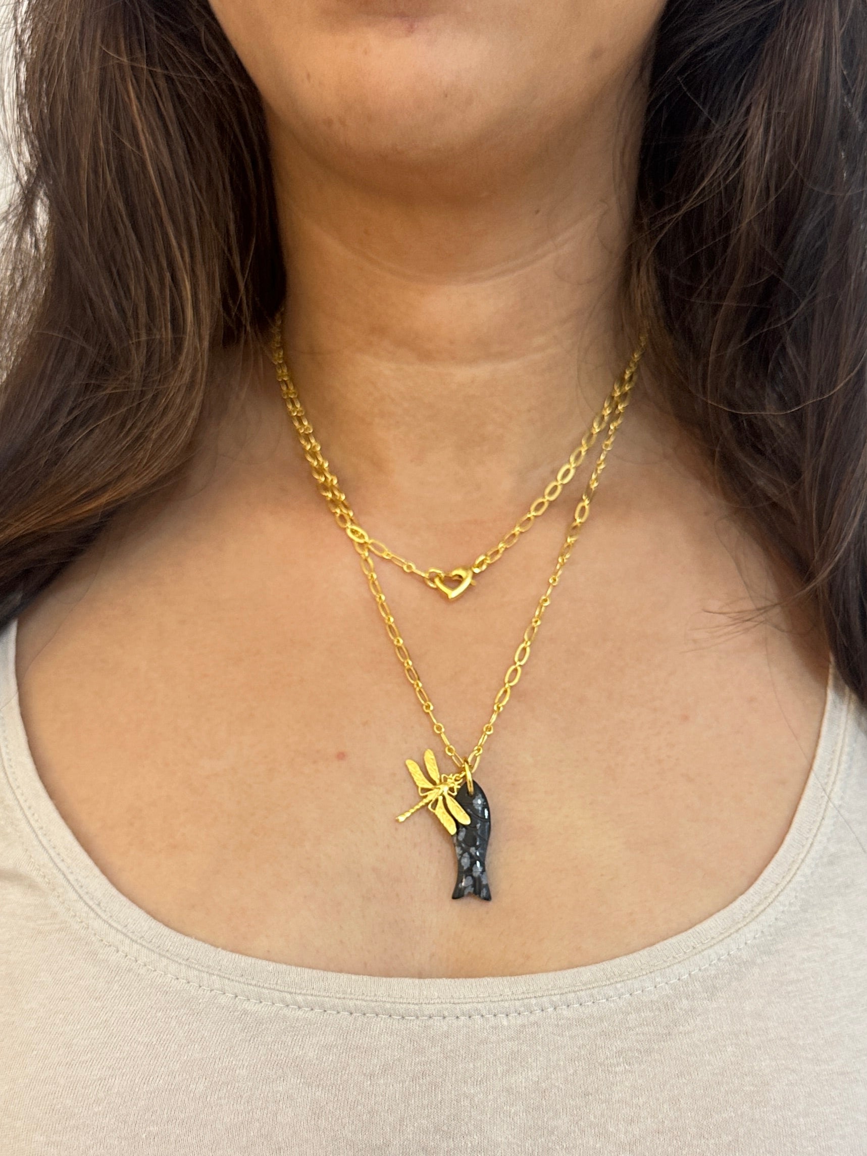 Woman wearing a gold necklace with a small pendant on a white background