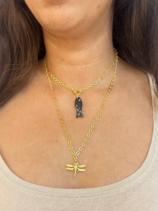 Woman wearing a gold necklace with a plain background