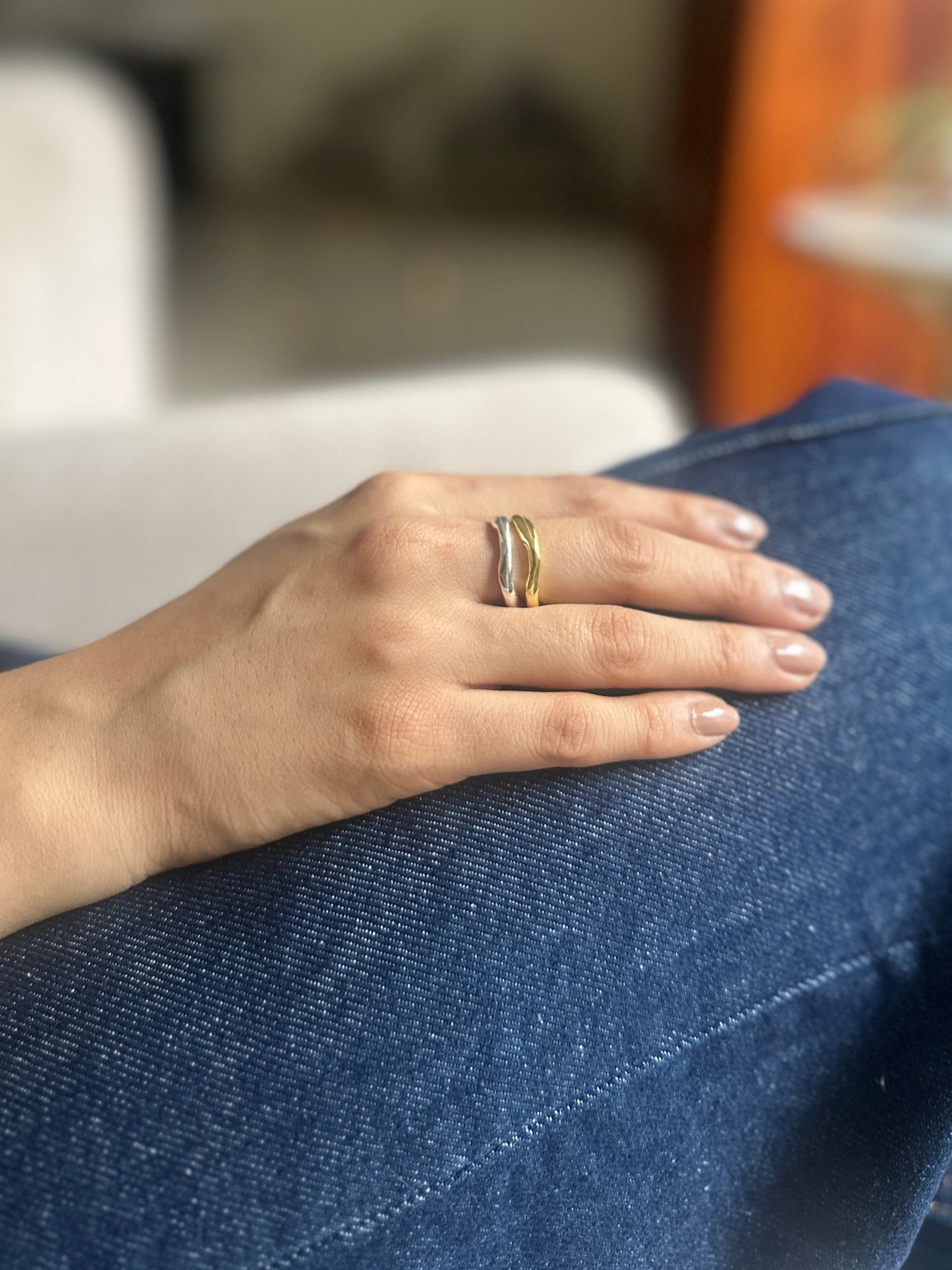 Hand with a ring on a knee in a blurred indoor setting