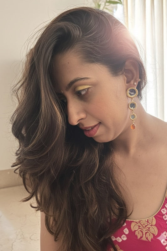 Woman with long wavy hair wearing colorful earrings indoors
