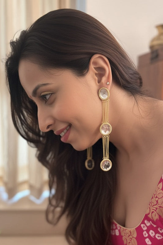 Woman wearing gold earrings with a blurred indoor background