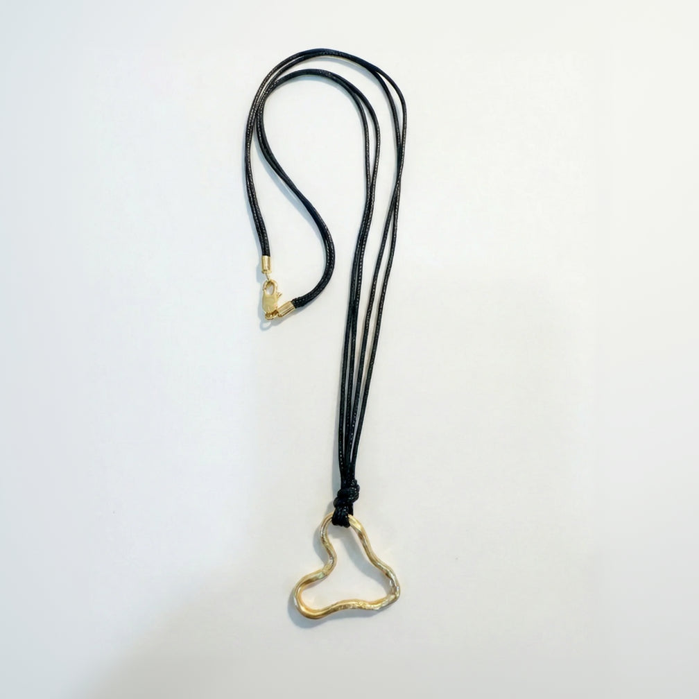 Necklace with black cord and gold heart-shaped clasp on a light gray background