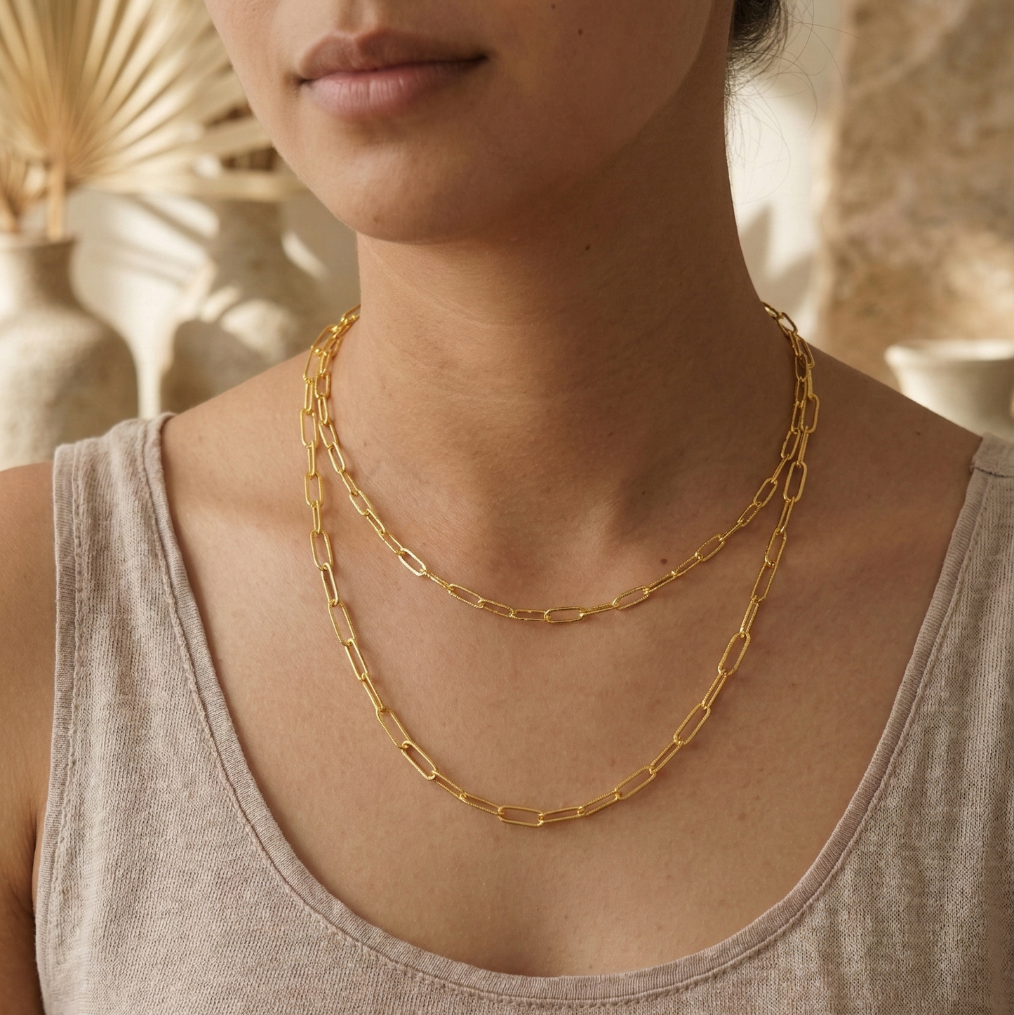 Woman wearing a gold chain necklace against a neutral background
