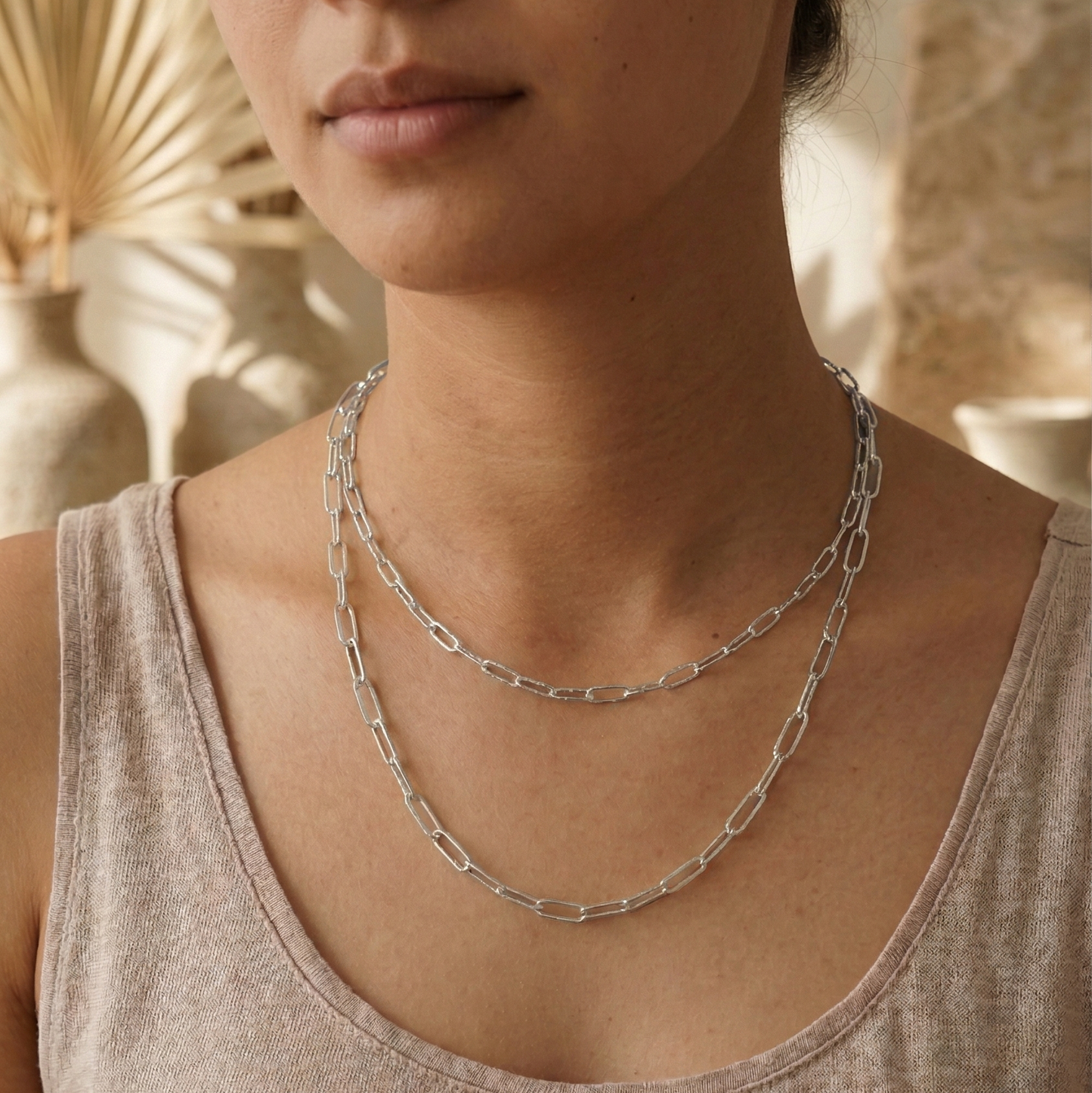 Woman wearing a silver chain necklace with a neutral background