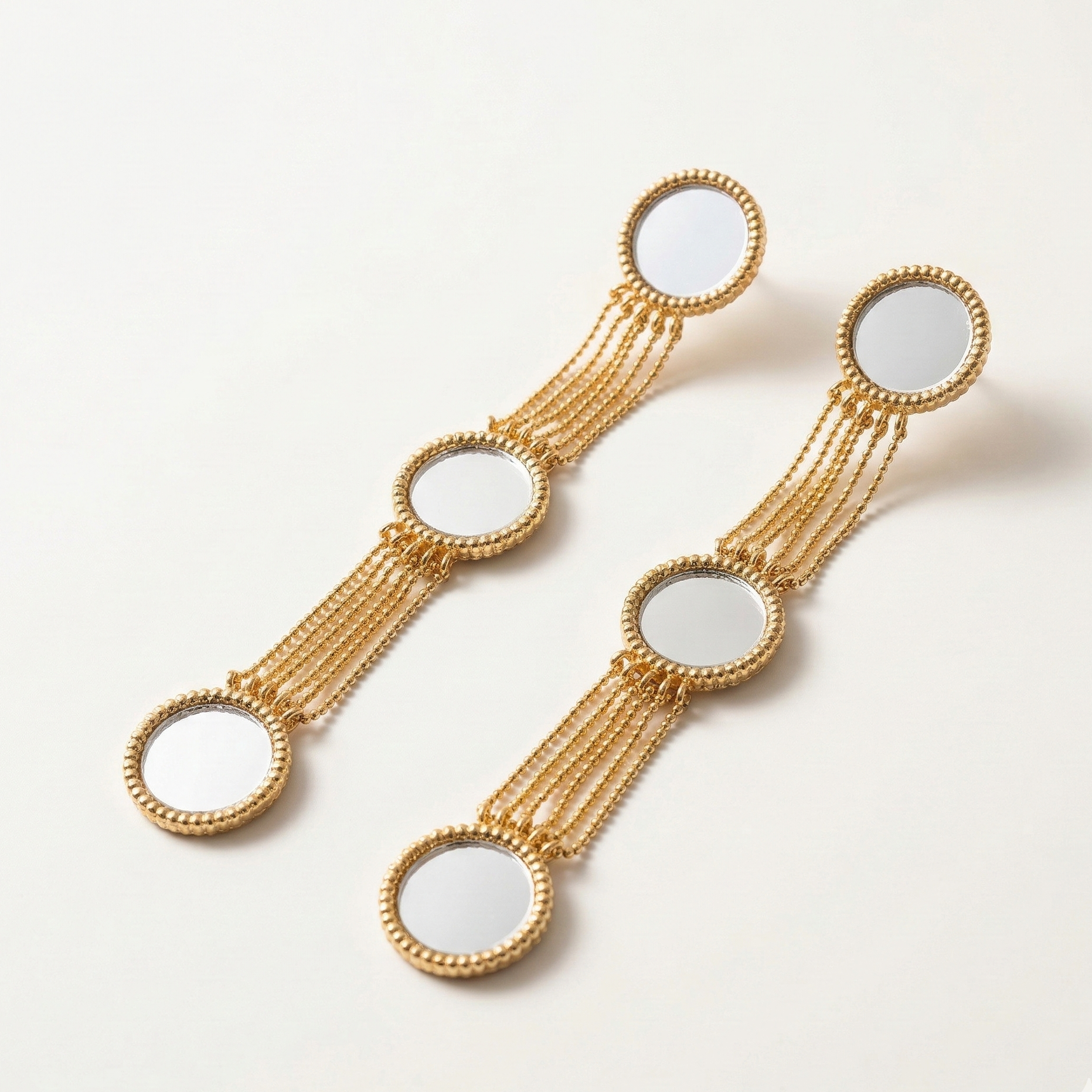 Gold earrings with circular designs on a light background