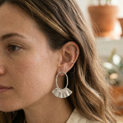 Woman wearing silver hoop earrings with a blurred indoor background