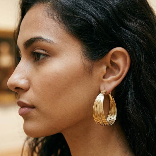Woman wearing gold hoop earrings with a blurred indoor background