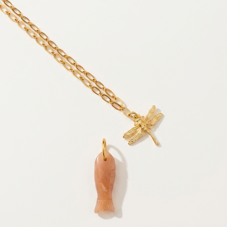 Gold necklace with a dragonfly pendant on a light background