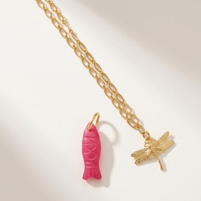 Gold chain necklace with pink fish and gold dragonfly pendants on a light background