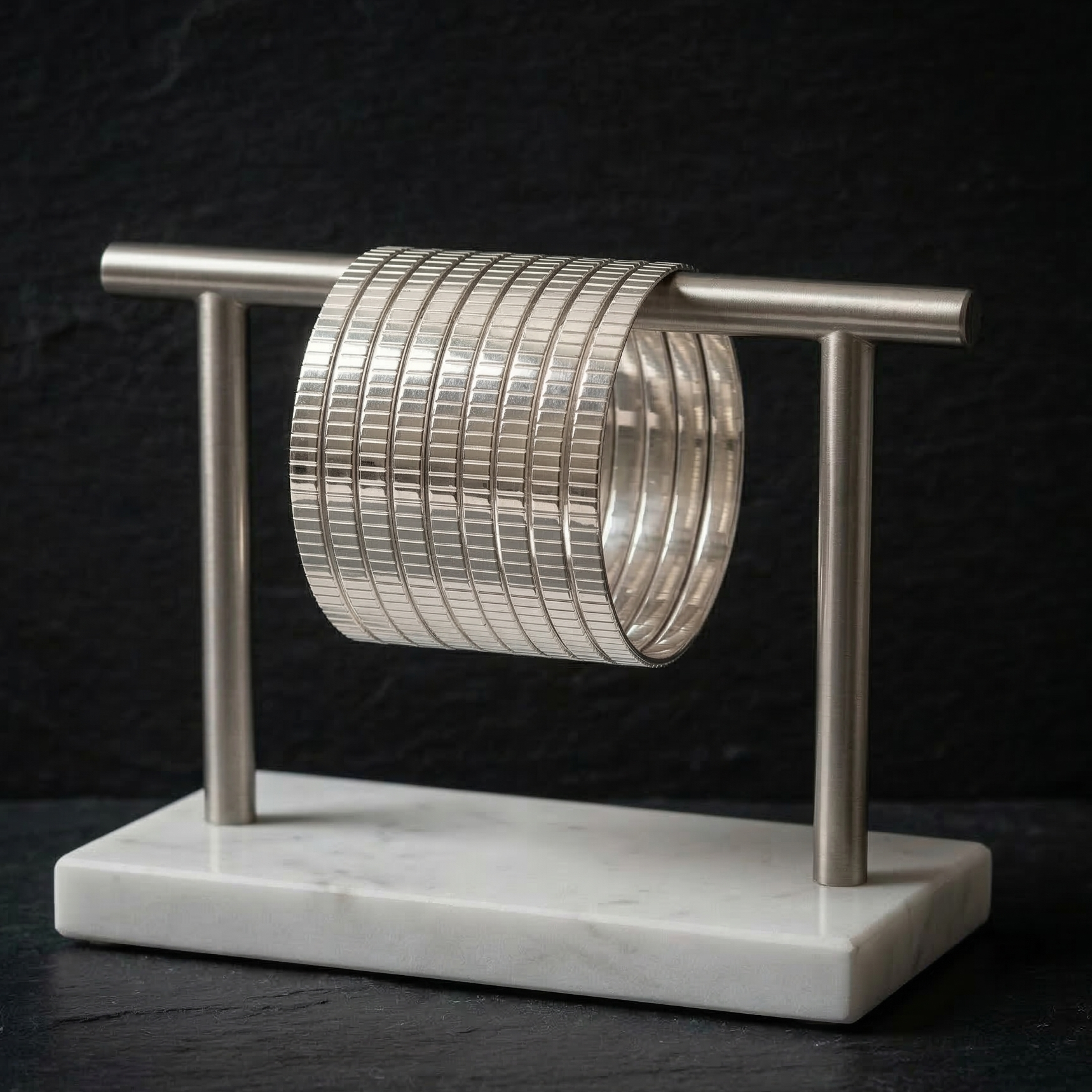 Stack of silver bangles on a marble stand against a dark background