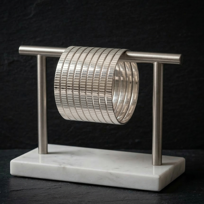 Stack of silver bangles on a marble stand against a dark background