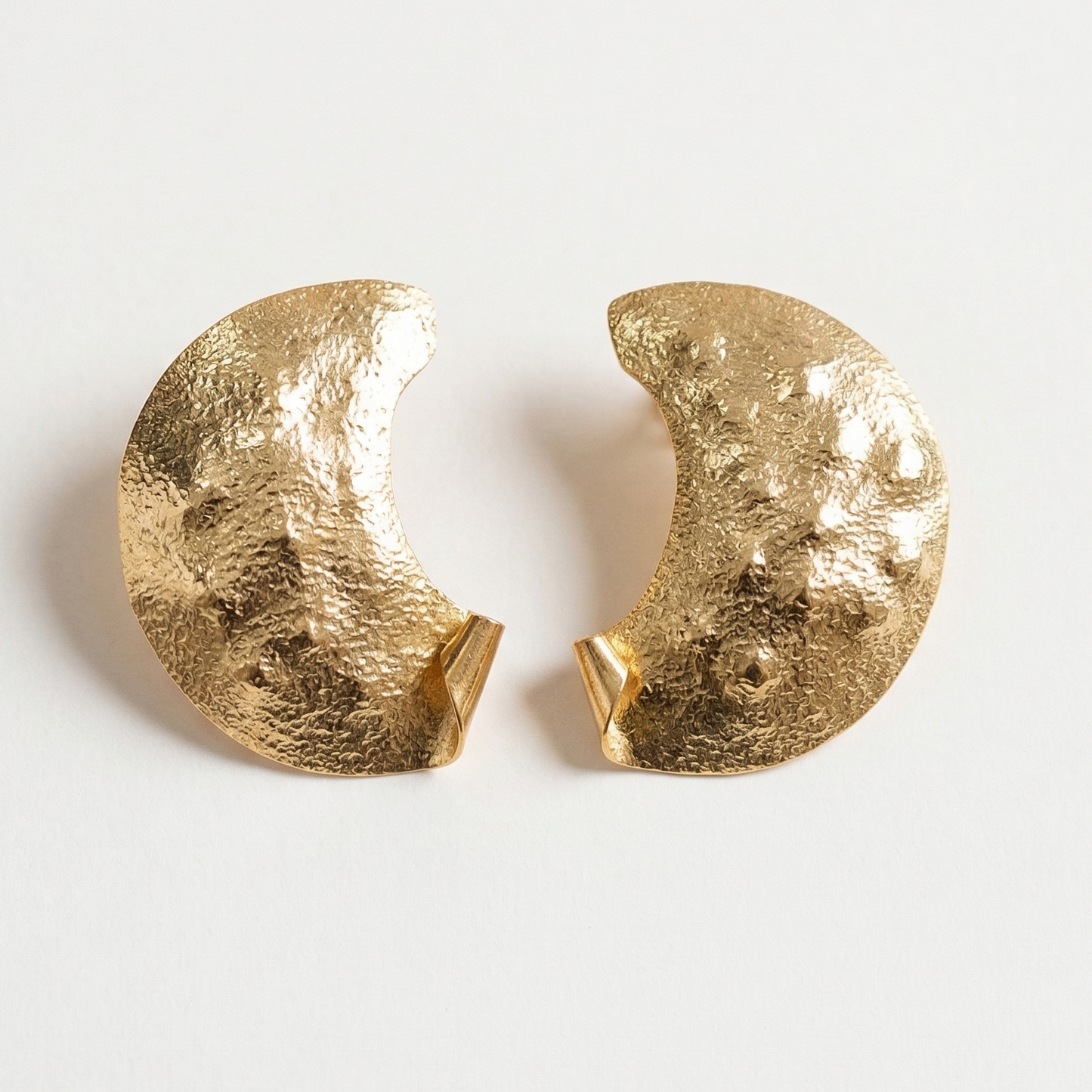 Pair of gold half moon earrings on a light gray background