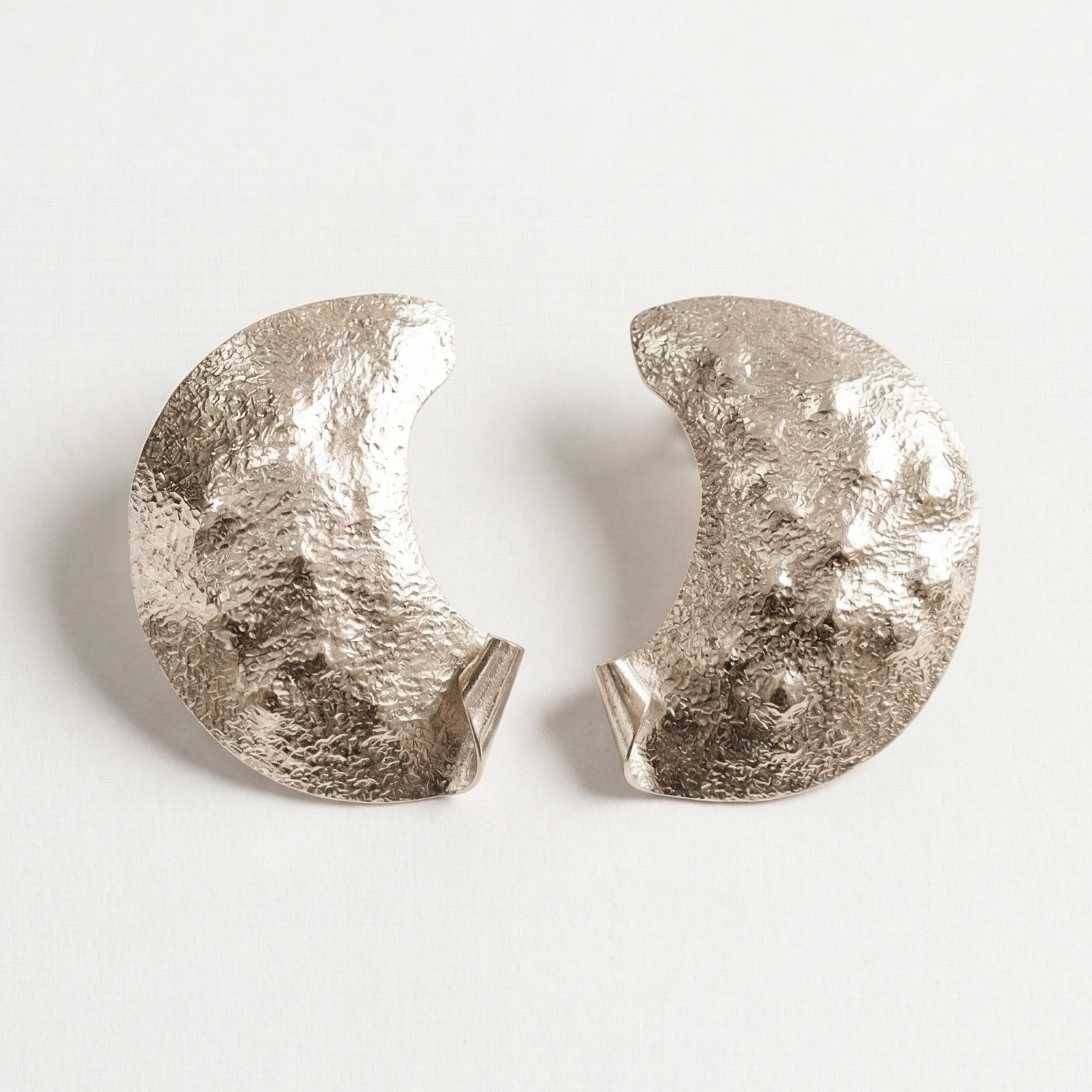 Pair of silver half moon earrings on a light gray background