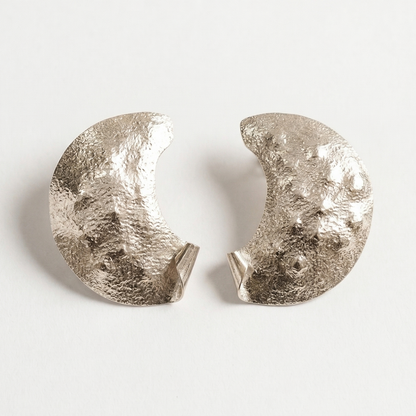 Pair of silver half moon earrings on a light gray background
