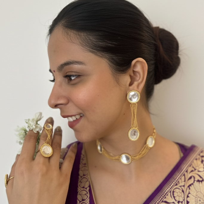 Woman wearing a purple saree with gold jewelry against a white background